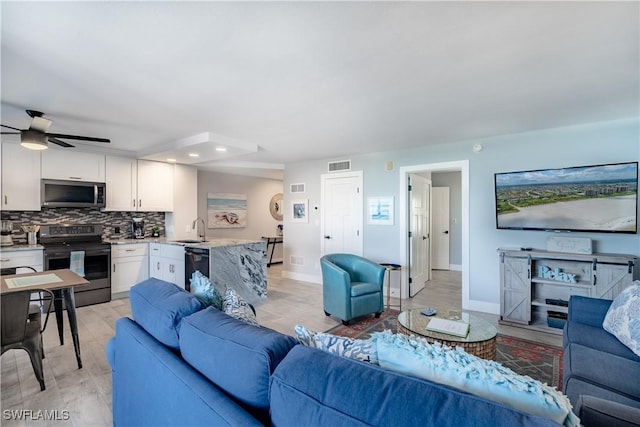 living room with sink, ceiling fan, and light hardwood / wood-style floors