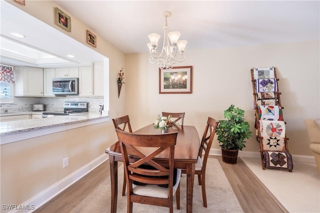 dining space with light hardwood / wood-style flooring and an inviting chandelier