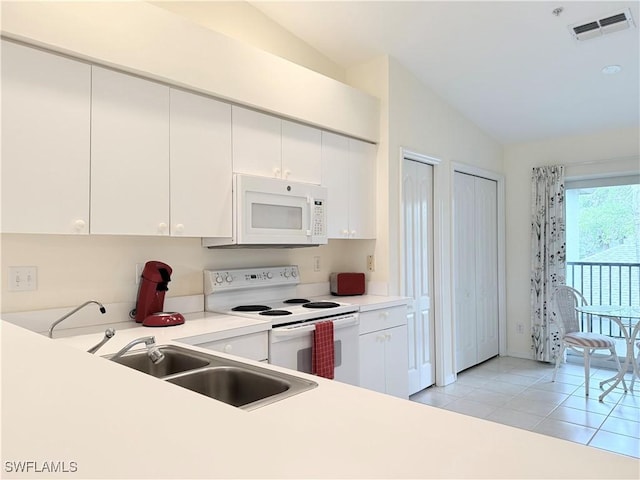 kitchen featuring sink, white cabinetry, lofted ceiling, white appliances, and light tile patterned flooring