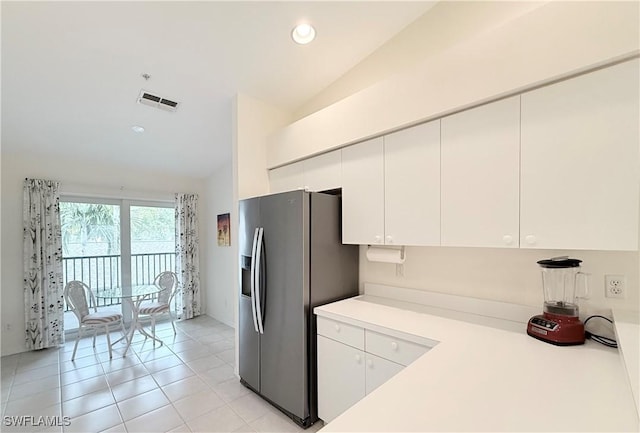 kitchen featuring lofted ceiling, stainless steel fridge with ice dispenser, light tile patterned floors, and white cabinetry