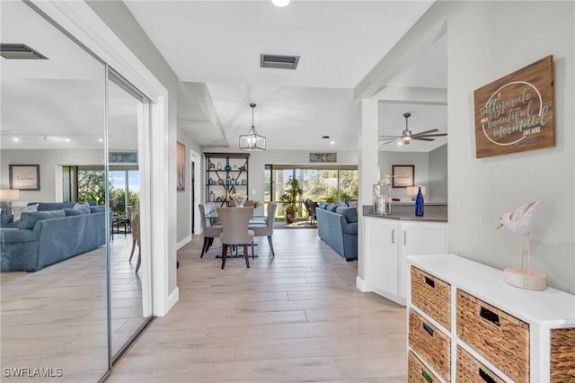 hall featuring an inviting chandelier, a wealth of natural light, and light hardwood / wood-style flooring