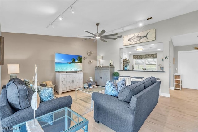 living room with lofted ceiling, light hardwood / wood-style flooring, rail lighting, and ceiling fan