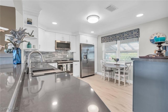 kitchen featuring sink, white cabinetry, tasteful backsplash, light wood-type flooring, and stainless steel appliances