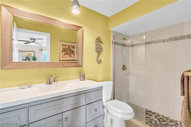 bathroom featuring vanity, a tile shower, ceiling fan, and toilet