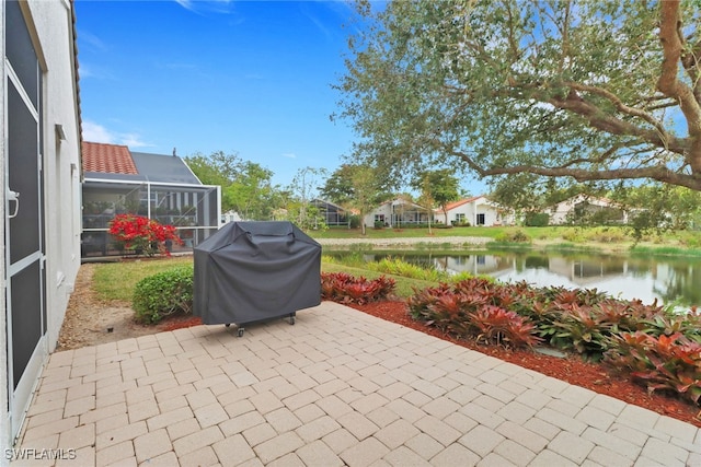 view of patio / terrace featuring a water view, glass enclosure, and area for grilling