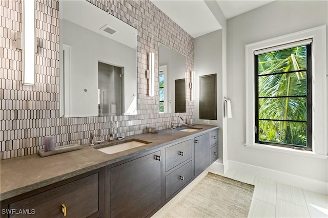 bathroom with a wealth of natural light, tile patterned floors, vanity, and tasteful backsplash