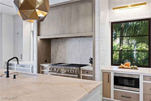 kitchen with double oven range, sink, built in microwave, ventilation hood, and light stone counters