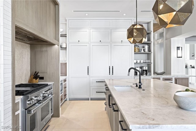 kitchen featuring light stone countertops, pendant lighting, white cabinetry, range with two ovens, and sink