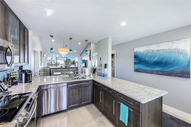 kitchen featuring light stone countertops, stainless steel appliances, sink, hanging light fixtures, and kitchen peninsula