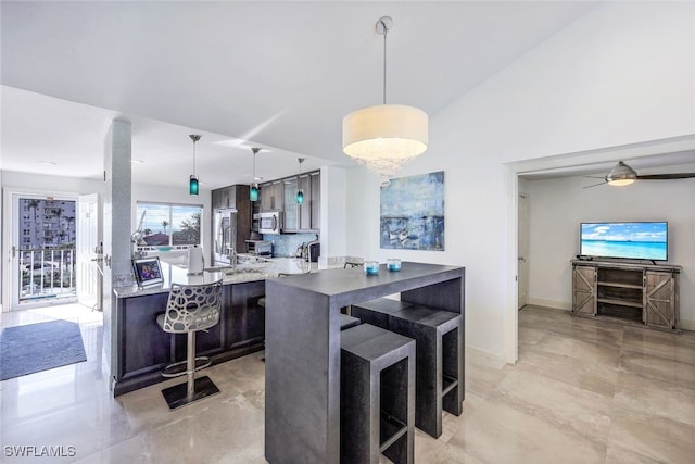 kitchen with decorative light fixtures, a breakfast bar, appliances with stainless steel finishes, and dark brown cabinets