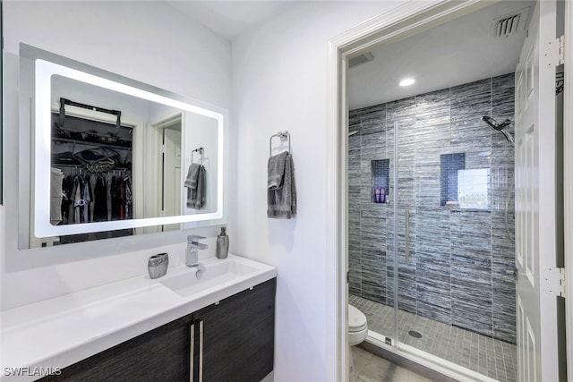 bathroom with toilet, a shower with door, tile patterned floors, and vanity