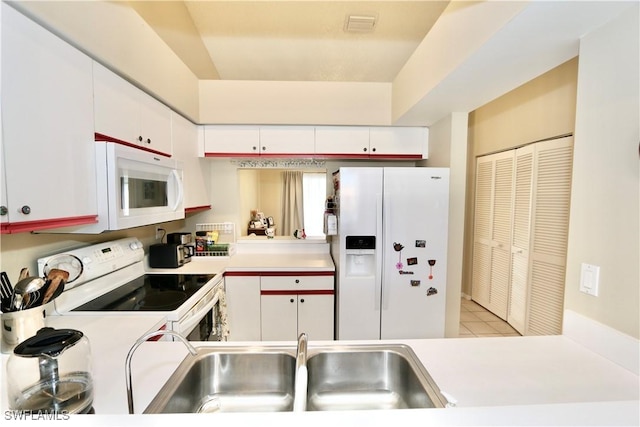 kitchen featuring light tile patterned floors, white cabinetry, sink, and white appliances