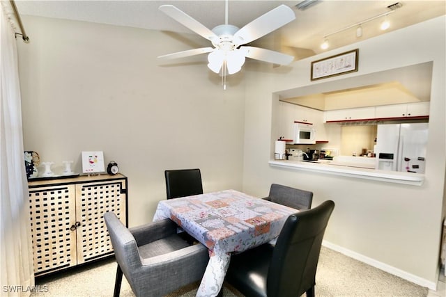 carpeted dining area with ceiling fan