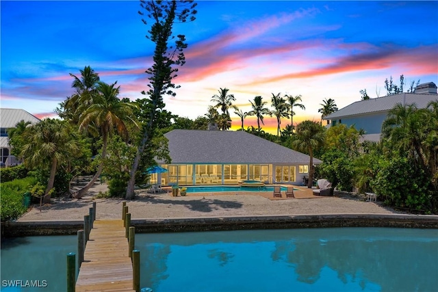 pool at dusk with a patio and a boat dock