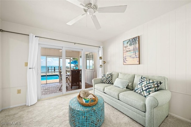 carpeted living room with a water view and ceiling fan