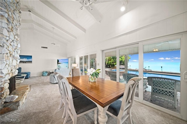 dining space featuring ceiling fan, beam ceiling, high vaulted ceiling, a water view, and light colored carpet