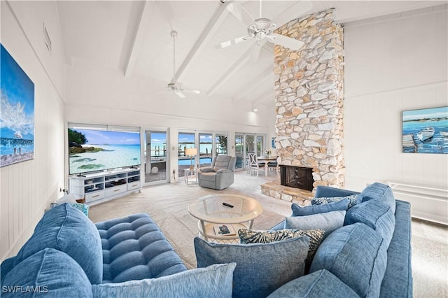 living room featuring ceiling fan, high vaulted ceiling, a stone fireplace, light colored carpet, and beamed ceiling