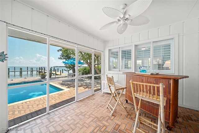 sunroom / solarium featuring a water view and ceiling fan