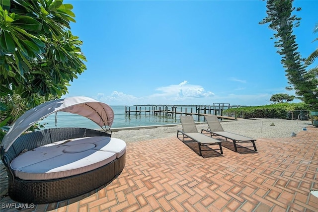 view of patio with a water view and a beach view