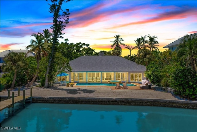 pool at dusk featuring an in ground hot tub and a patio area