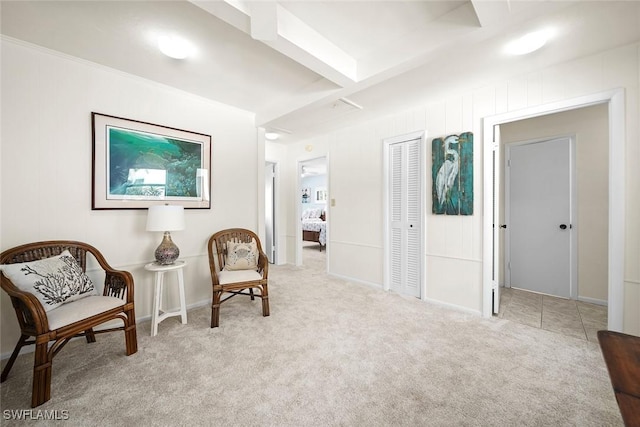 sitting room with beam ceiling and light colored carpet