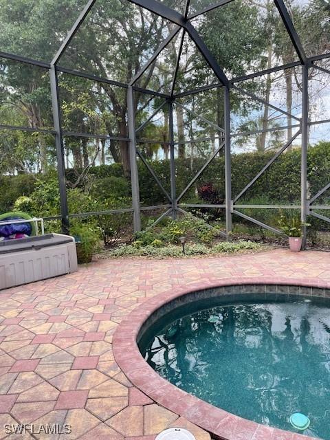 view of swimming pool with a patio and glass enclosure