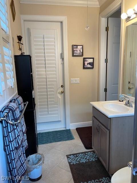 bathroom with a healthy amount of sunlight, tile patterned flooring, crown molding, and vanity