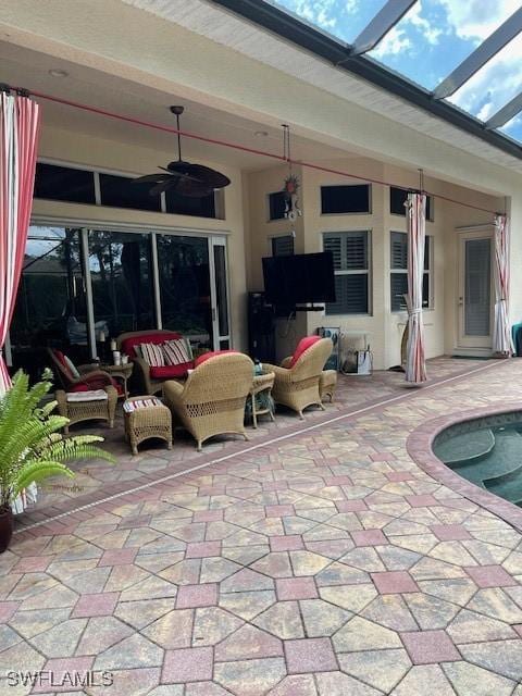 view of patio with an outdoor hangout area, ceiling fan, and glass enclosure