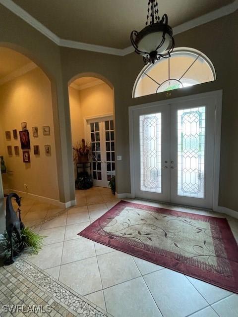 entryway with french doors, crown molding, and tile patterned floors