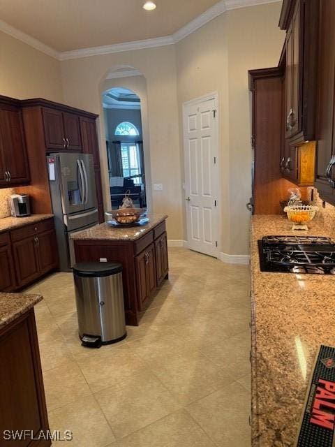 kitchen featuring appliances with stainless steel finishes, a center island, ornamental molding, and light stone countertops