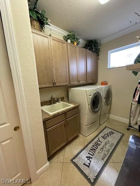 washroom with cabinets, light tile patterned floors, washer and clothes dryer, and sink