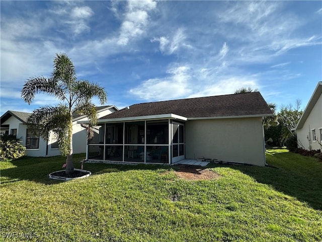 back of property with stucco siding, a lawn, and a sunroom