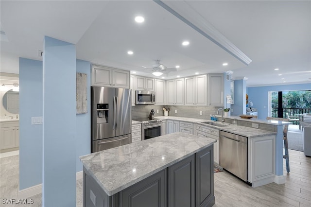 kitchen featuring ceiling fan, appliances with stainless steel finishes, sink, and a center island