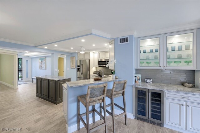 kitchen featuring stainless steel appliances, visible vents, a kitchen island, and light stone countertops