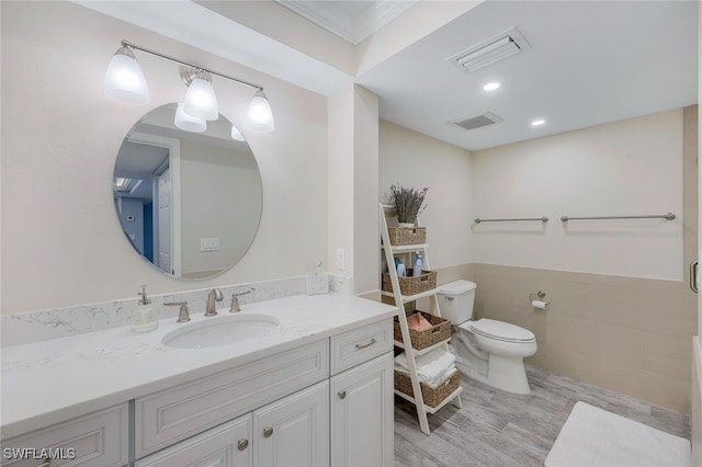 bathroom featuring toilet, visible vents, tile walls, and wainscoting