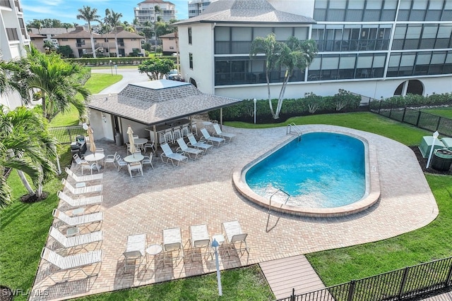 view of swimming pool featuring a lawn, an outdoor bar, and a patio area