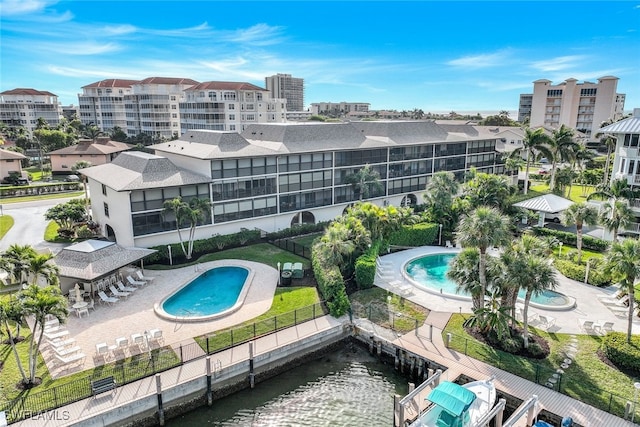 view of pool featuring a water view, a dock, and a patio area