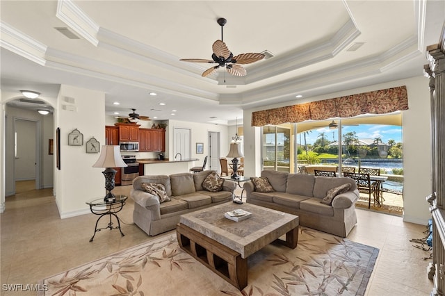 tiled living room featuring crown molding, a tray ceiling, and ceiling fan