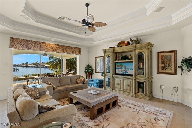 tiled living room featuring crown molding, a water view, ceiling fan, and a tray ceiling