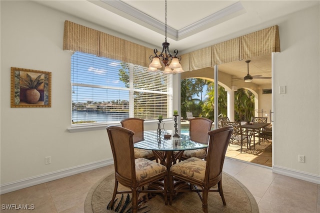 dining space featuring crown molding, a water view, light tile patterned floors, and a tray ceiling