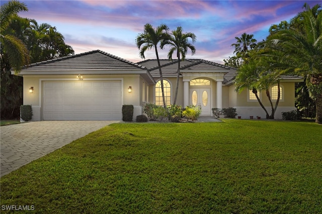 view of front of property with a garage and a lawn