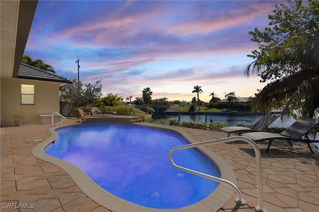 pool at dusk with a patio and a water view