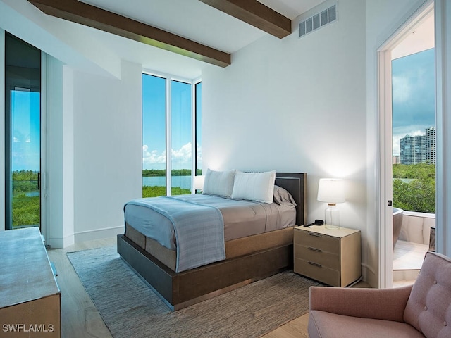 bedroom with multiple windows, beam ceiling, and light hardwood / wood-style flooring