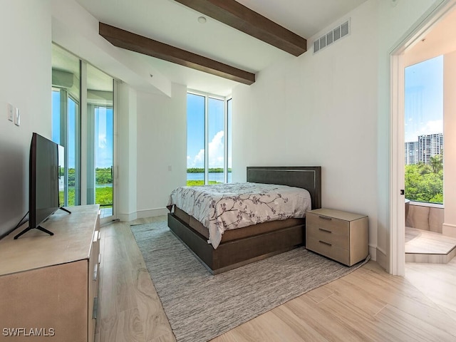 bedroom featuring access to exterior, beam ceiling, and light hardwood / wood-style flooring