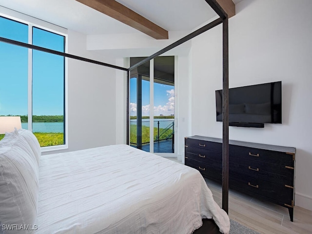 bedroom featuring a water view, beam ceiling, light hardwood / wood-style floors, and multiple windows