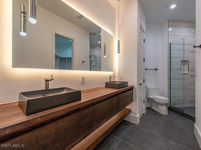 bathroom featuring vanity, toilet, tile patterned floors, and a shower with shower door