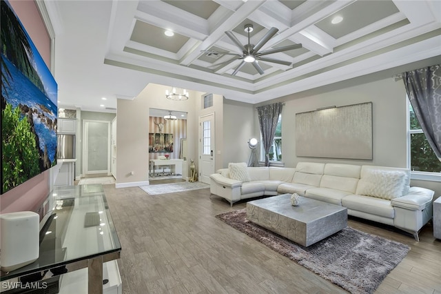 living room featuring coffered ceiling, light wood-type flooring, ornamental molding, beam ceiling, and ceiling fan with notable chandelier