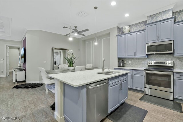 kitchen featuring sink, light wood-type flooring, an island with sink, pendant lighting, and stainless steel appliances