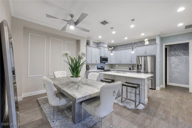 dining area featuring ceiling fan, wood-type flooring, sink, and ornamental molding