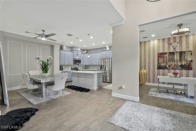 kitchen featuring gray cabinetry, tasteful backsplash, light hardwood / wood-style flooring, a kitchen island, and stainless steel appliances